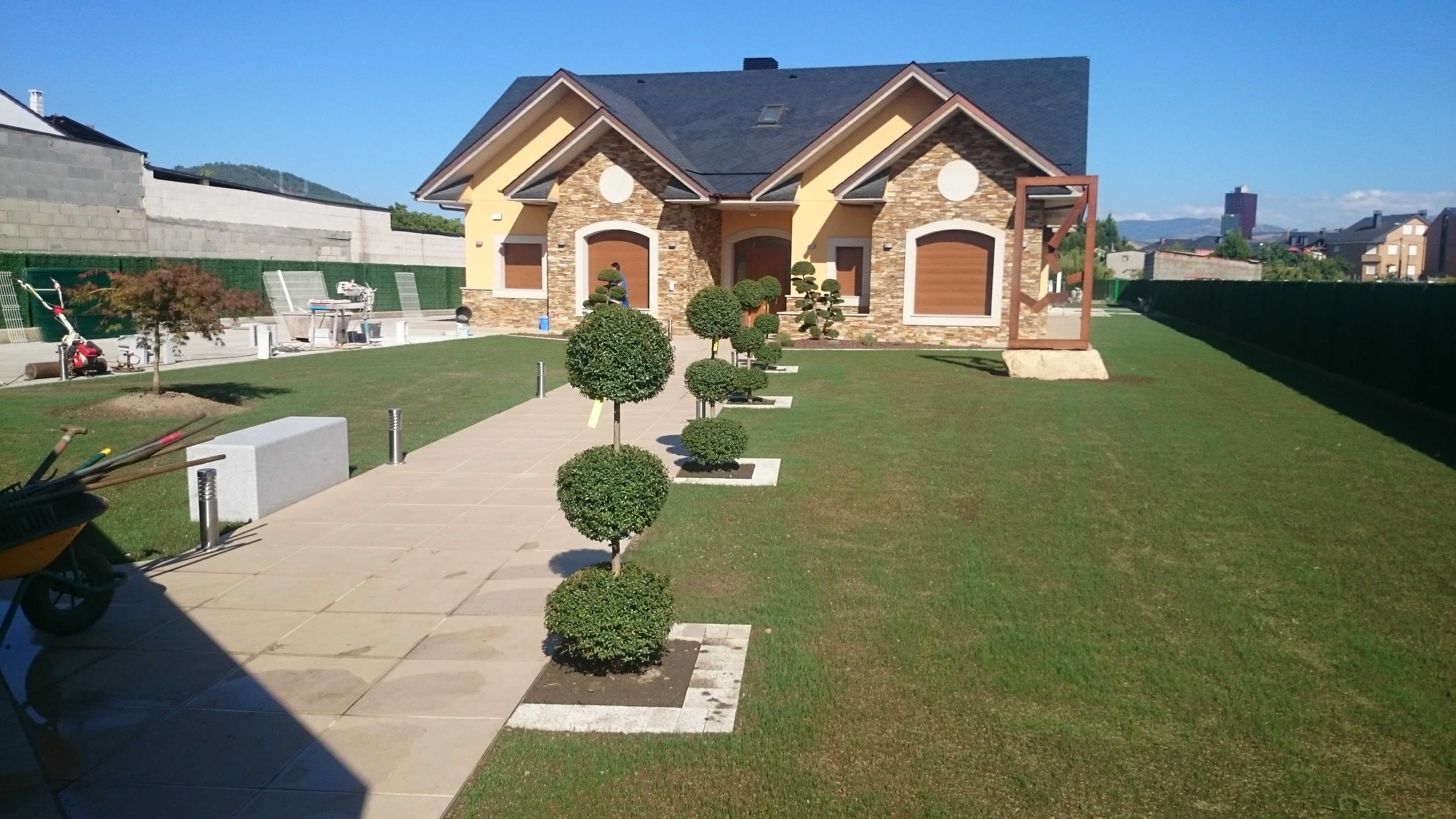 Entrada residencial con topiarias y diseño paisajístico